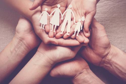 Mãos protegendo figuras que representam uma família
